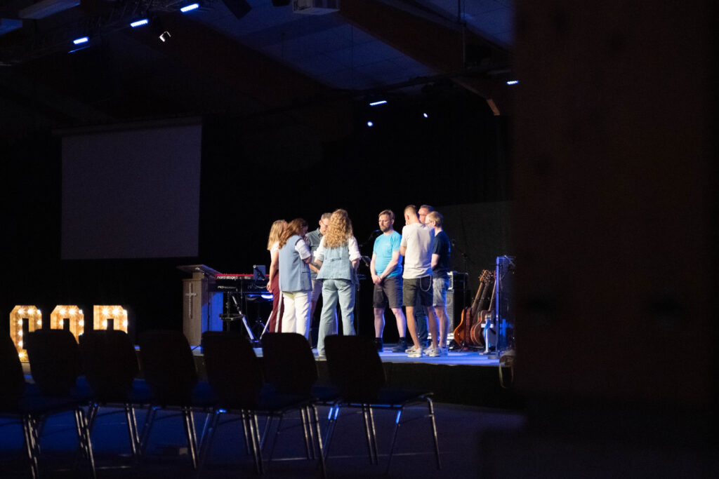 Het organisatieteam bidt samen op het podium