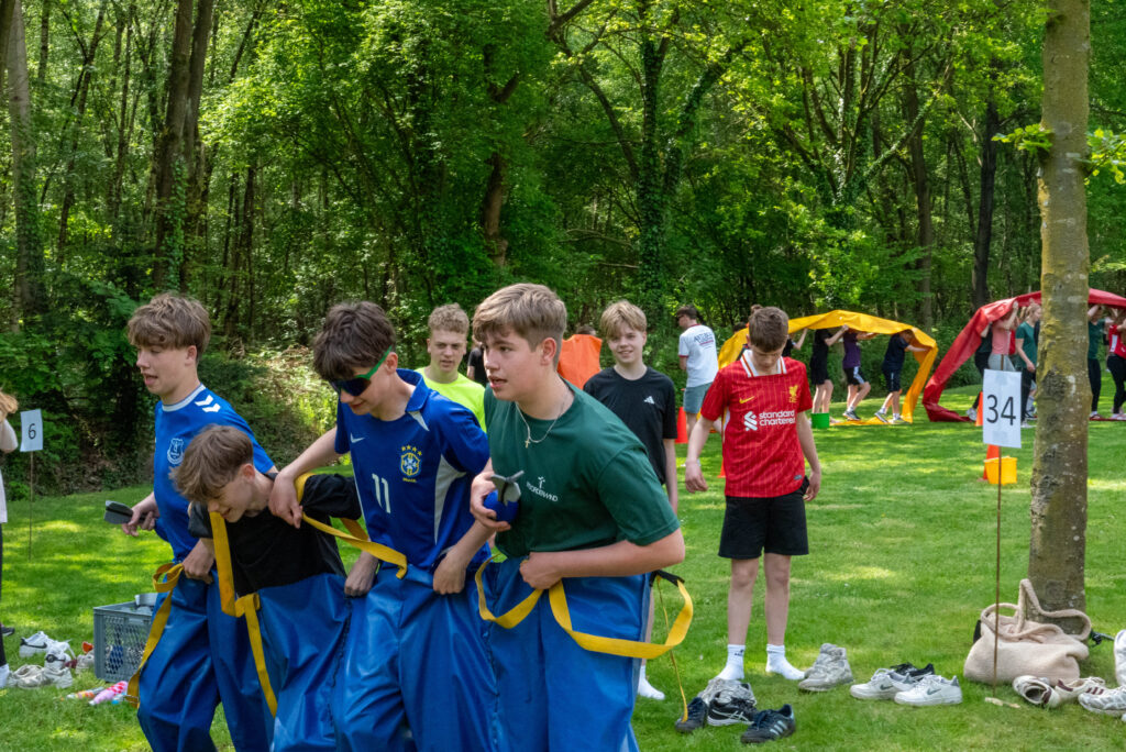 Tieners doen mee aan een zaklopen-estafette in het bos