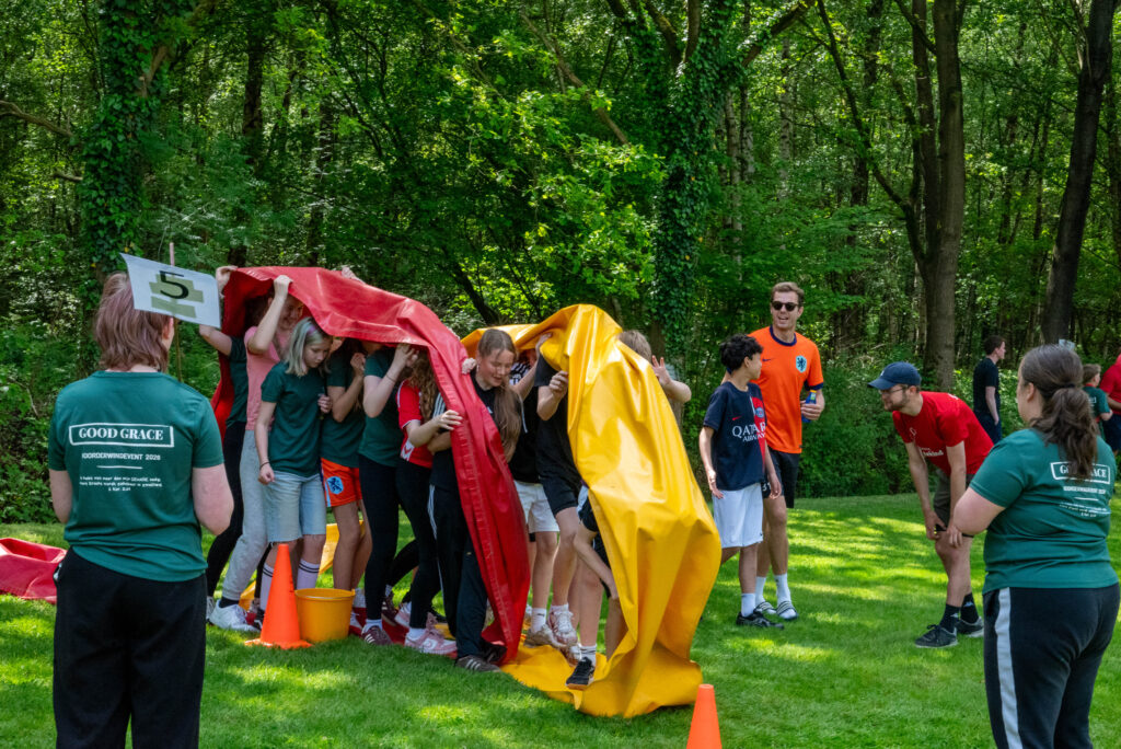 Deelnemers spelen een groepsspel met een doek tijdens Noorderwind