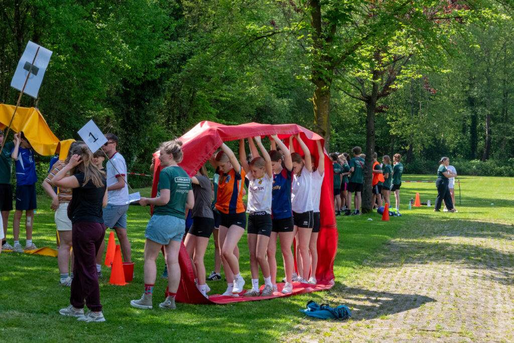 Deelnemers vormen een tunnel met een doek tijdens een teamspel